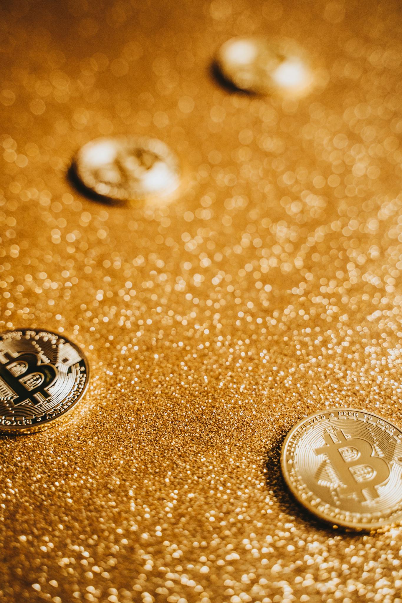 Close-up of Bitcoin coins on a glittering gold background.